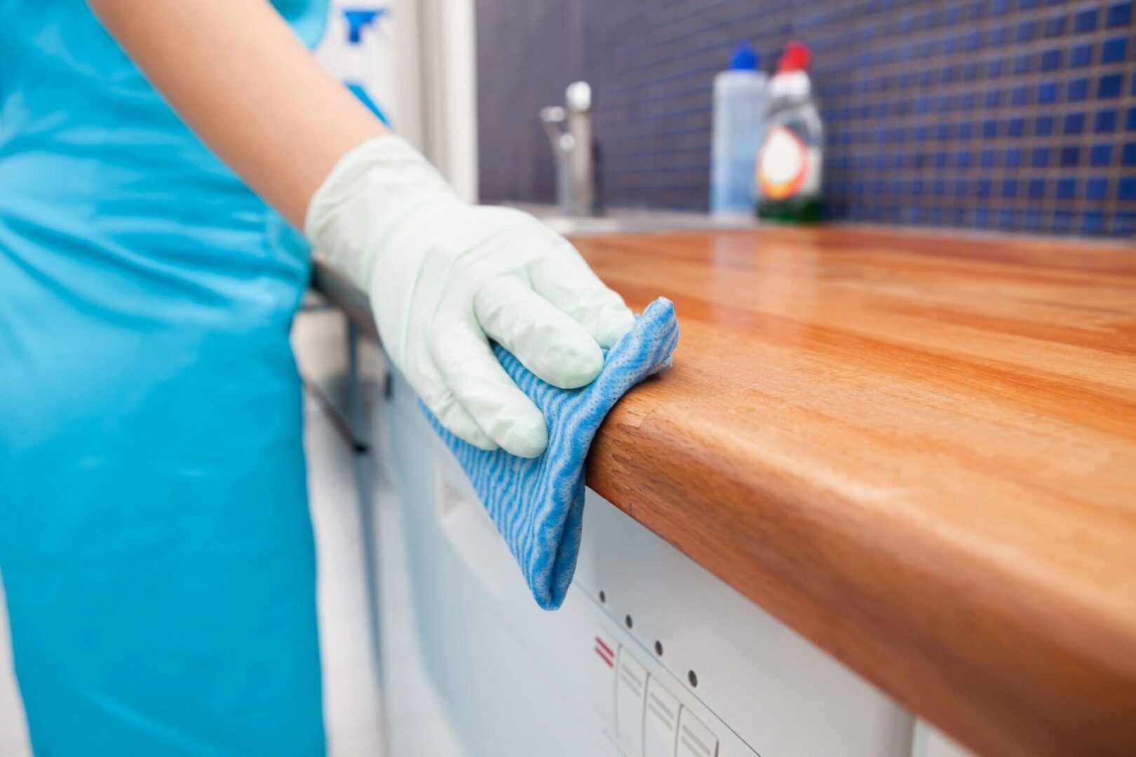 A person cleaning the counter top of a kitchen.