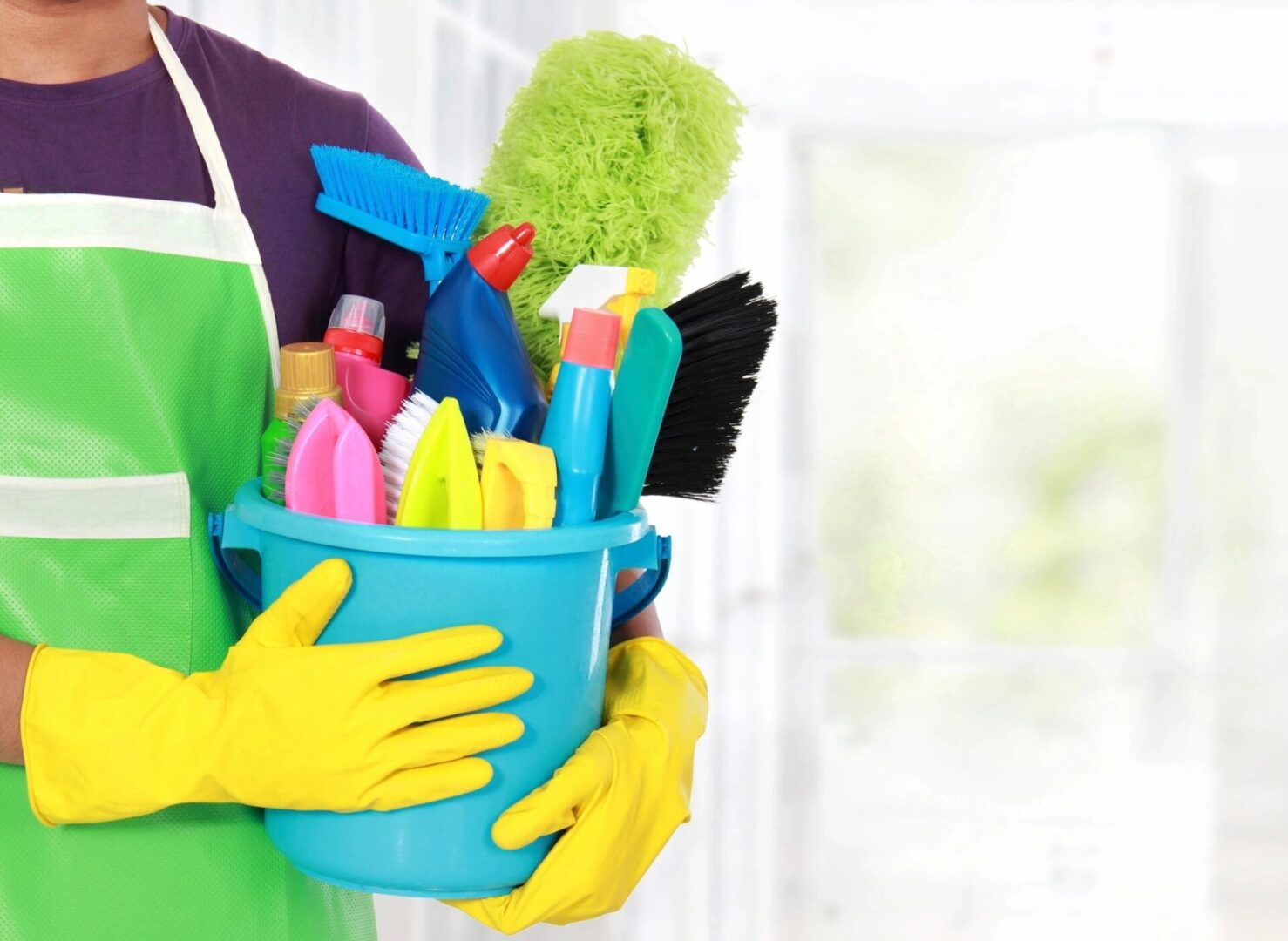 A person holding a bucket of cleaning supplies.